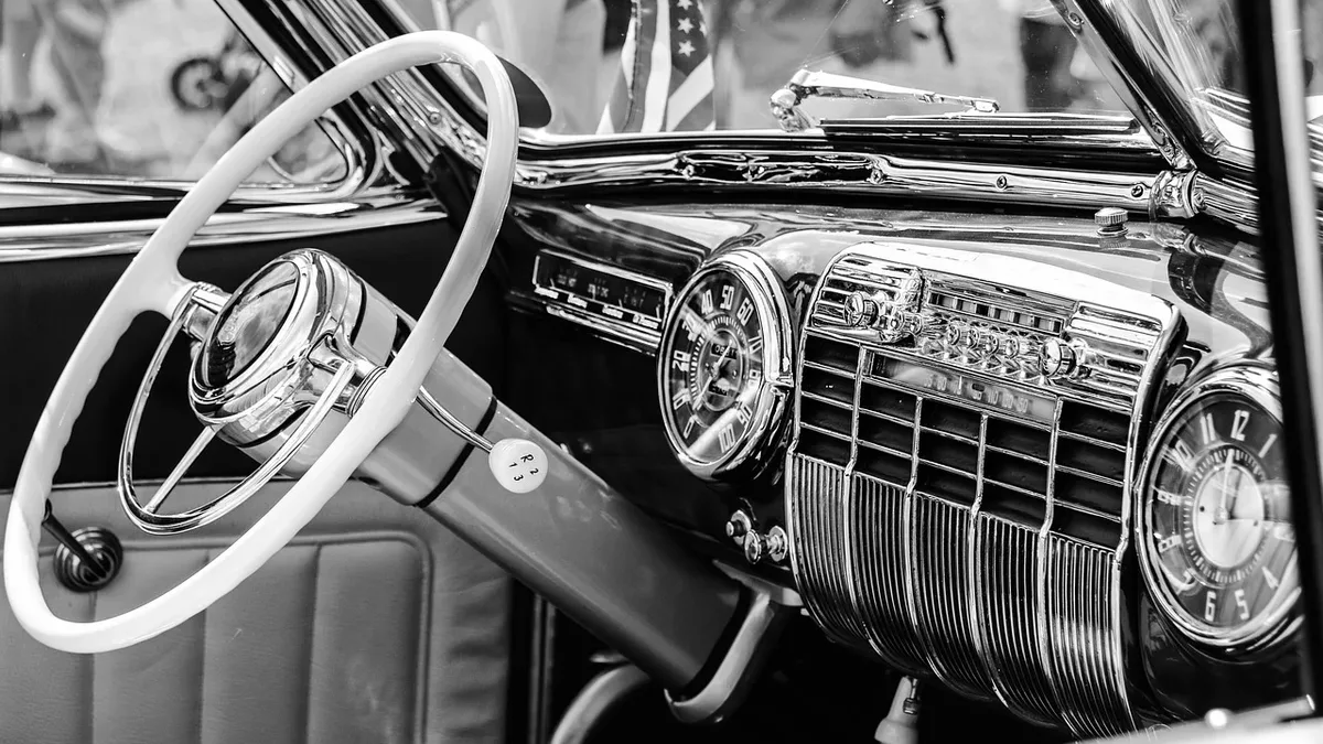 The interior of a vintage car, specifically the steering wheel, dashboard, and front seats.
