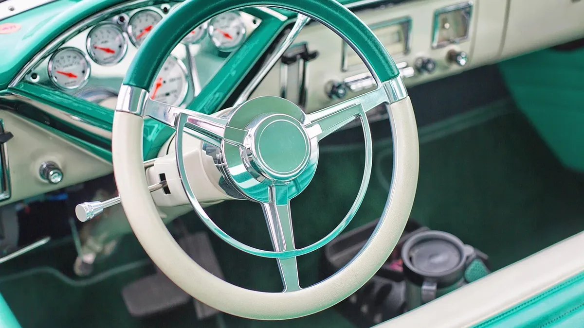 The interior of a vintage car, specifically the steering wheel and dashboard.